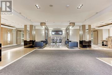 Toronto (York University Heights) condo for rent - A spacious living room with a grey carpet and a television in the middle.