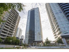 Surrey apartment for rent - A tall building with many windows stands in the middle of a city street.