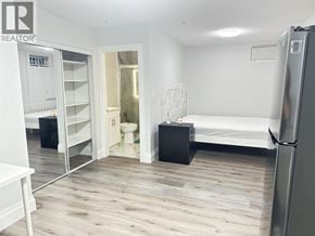 Vancouver apartment for rent - A white bedroom with a bed, dresser, and a fridge.