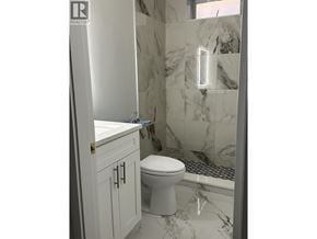 Vancouver apartment for rent - A white toilet in a bathroom with a marble wall.