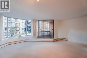 Vancouver apartment for rent - A large, empty room with a view of a cityscape through large windows.