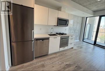 Toronto (Moss Park) condo for rent - A modern kitchen with a stainless steel refrigerator and wooden flooring.