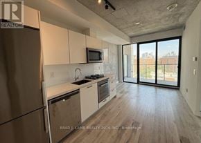 Toronto (Moss Park) condo for rent - A kitchen with a refrigerator, microwave, oven, and sink.