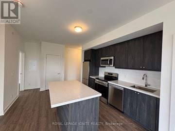 Clarington (Bowmanville) condo for rent - A kitchen with dark wood cabinets and a white island.