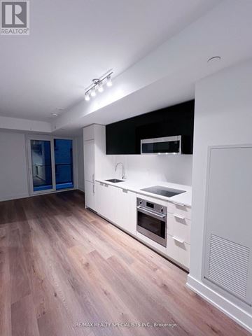 Toronto (Church-Yonge Corridor) condo for rent - A modern kitchen with wooden floors and white cabinetry.