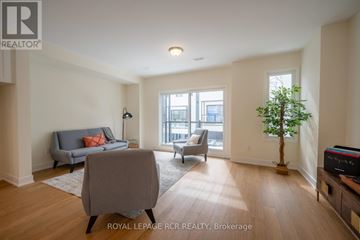 Orillia townhouse for rent - A living room with a grey couch, a small table, and a plant.