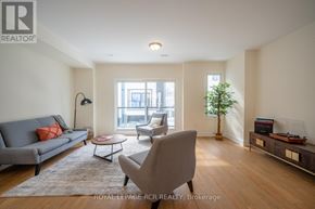 Orillia townhouse for rent - A living room with a grey couch, a coffee table, a chair, and a plant.