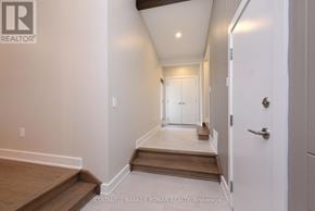 New Tecumseth multi-family for rent - A hallway with a door on the right and a staircase on the left.