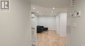 Ottawa apartment for rent - A spacious room with a black sofa and wooden flooring.
