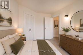 Toronto (Woodbine Corridor) condo for rent - A well-lit bedroom with a large bed, a side table with a lamp, and a dresser with a mirror above it.