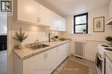 Toronto (Woodbine Corridor) condo for rent - A kitchen with white cabinets and a marble countertop.