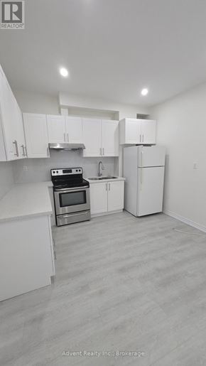 Toronto (Roncesvalles) apartment for rent - A white kitchen with a stove top oven and a refrigerator.