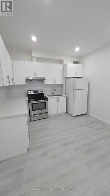 Toronto (Roncesvalles) apartment for rent - A white kitchen with a stove top oven and a refrigerator.