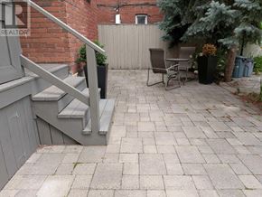 Toronto (Palmerston-Little Italy) apartment for rent - A patio with a table and chairs is surrounded by a brick wall.