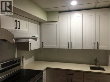Coquitlam apartment for rent - A kitchen with white cabinets and a black countertop.