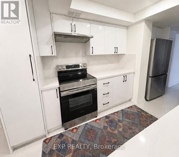 Toronto (L'amoreaux) condo for rent - A kitchen with white cabinets and a black stove top oven.