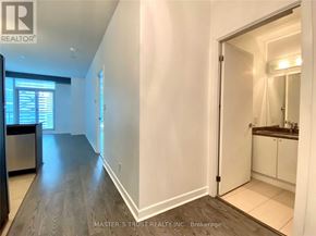 Toronto (Waterfront Communities) condo for rent - A hallway with a wooden floor and white walls leading to a bathroom.