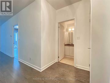 Toronto (Waterfront Communities) condo for rent - A white hallway with a doorway leading to a kitchen area.