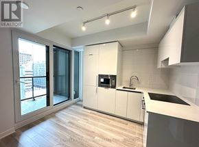Toronto (Kensington-Chinatown) condo for rent - A modern kitchen with white cabinets and a wooden floor.