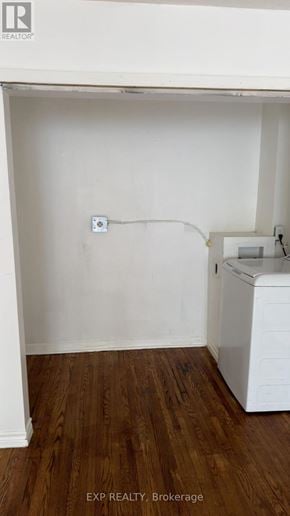 Toronto (Cliffcrest) fourplex for rent - A white wall with a socket and a washing machine in a room with wooden flooring.