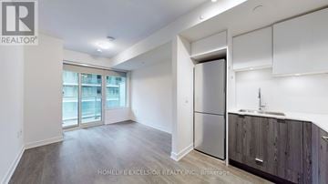 Toronto (Mount Pleasant West) condo for rent - A spacious kitchen with wooden cabinets and a stainless steel refrigerator.