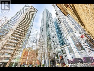 Toronto (Annex) condo for rent - A tall building with a glass facade stands in front of a construction site.