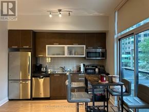 Toronto (Church-Yonge Corridor) condo for rent - A kitchen with a refrigerator, microwave, oven, sink, and dining table.