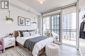 Toronto (Yonge-Eglinton) condo for rent - A bedroom with a large bed, a pink chair, and a window with blinds.