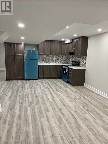 Brampton (Bram East) apartment for rent - A kitchen with a blue fridge and wooden cabinets.