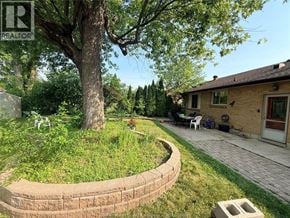 Windsor apartment for rent - A backyard with a curved brick wall and a tree.