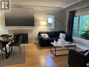 Vancouver apartment for rent - A living room with a black couch, a fireplace, and a television.