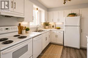 Welland (N. Welland) apartment for rent - A white kitchen with a refrigerator, stove, and sink.