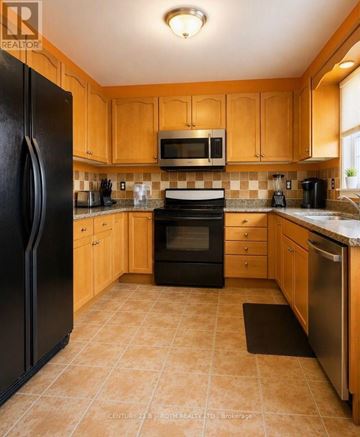 Barrie (East Bayfield) apartment for rent - A kitchen with wooden cabinets and black appliances.