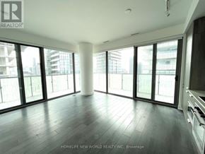 Toronto (Church-Yonge Corridor) condo for rent - A spacious room with wooden flooring and large windows overlooking a cityscape.