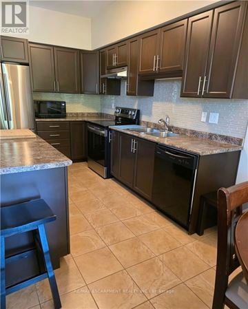 Grimsby (Grimsby Beach) townhouse for rent - A kitchen with brown cabinets and black appliances.