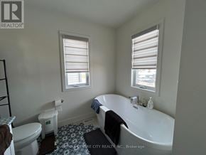London North (North S) multi-family for rent - A white bathroom with a toilet, a bathtub, and a window.