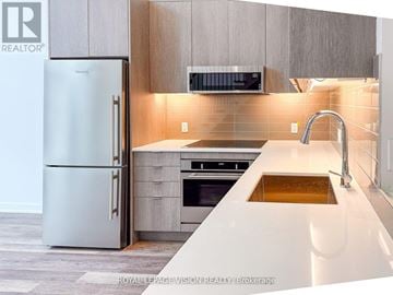 Toronto (Lawrence Park North) townhouse for rent - A modern kitchen with a white refrigerator and a stainless steel oven.