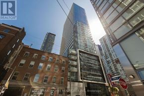 Toronto (Waterfront Communities) condo for rent - A tall building with a glass facade stands in the middle of a city street.
