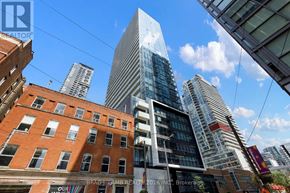 Toronto (Waterfront Communities) condo for rent - A cityscape with a mix of modern and older buildings, with the skyline dominated by a tall glass skyscraper.