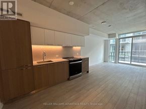 Toronto (South Riverdale) condo for rent - A spacious kitchen with wooden cabinets and a black stove top oven.