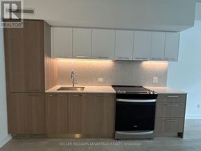 Toronto (South Riverdale) condo for rent - A modern kitchen with wooden cabinets and a stainless steel dishwasher.