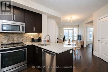 Toronto (High Park-Swansea) condo for rent - A kitchen with a stove top oven and microwave, a sink and a dining table with chairs.