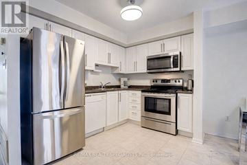 Mississauga (Churchill Meadows) townhouse for rent - A kitchen with a stainless steel refrigerator and white cabinets.