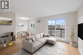Windsor condo for rent - A living room with a grey sofa and a painting on the wall.