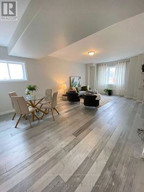 Barrie (Letitia Heights) multi-family for rent - A living room with a wooden floor and a dining table with chairs.