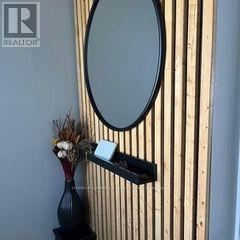 Guelph (Grange Road) apartment for rent - A round mirror is mounted on a wooden wall above a black vase with dried flowers.