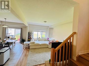 Brantford apartment for rent - A living room with a white couch and a dining table.