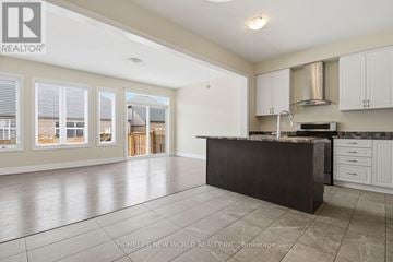Niagara Falls (Lyons Creek) apartment for rent - A spacious kitchen with white cabinets and a black countertop.