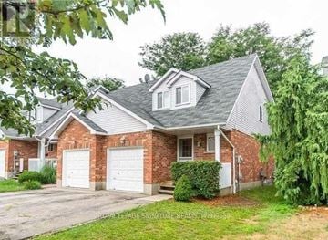 Waterloo townhouse for rent - A house with a brick facade and a grey roof is surrounded by greenery.