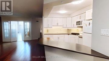 London East (East F) condo for rent - A modern kitchen with white cabinets and a wooden floor.